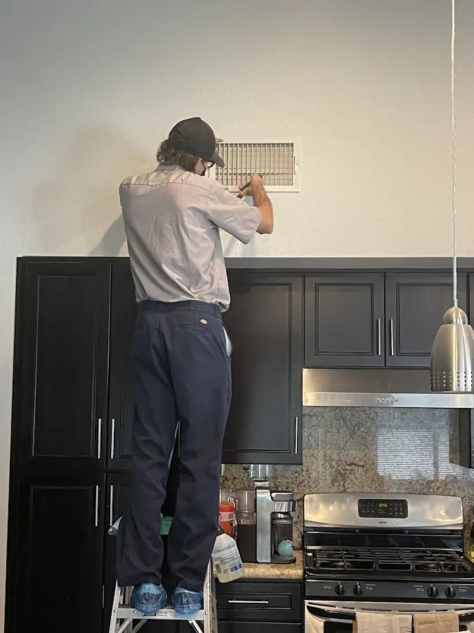 Technician inspecting an air vent during HVAC service in Kingston